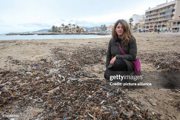 March 2018, Spain, Mallorca: Resident Aina Barcelò crouching on the beach where rubbish, mixed with sanitary products, is mixed with Neptune grass....