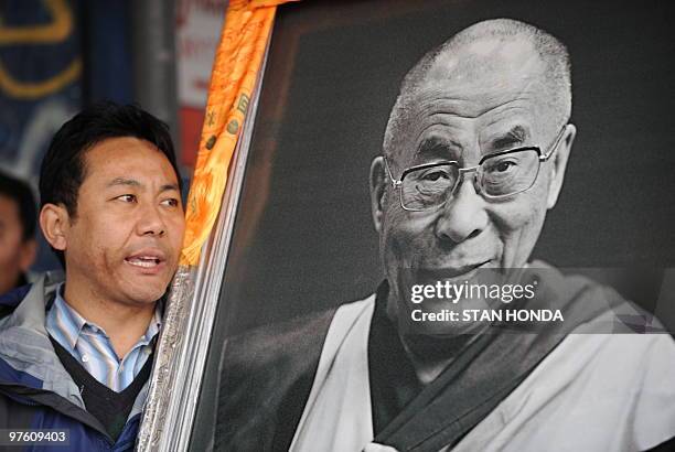 Tibetan protesters hold a photograph of the Dali Lama as they march up Third Avenue March 10, 2010 in New York to mark the 51st anniversary of...