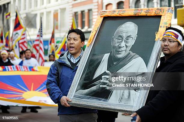 Tibetan protesters hold a photograph of the Dali Lama as they march up Third Avenue March 10, 2010 in New York to mark the 51st anniversary of...