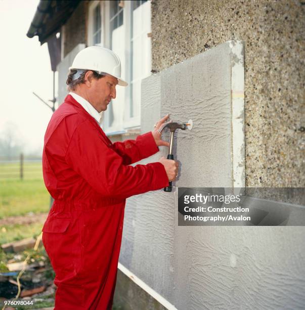 Builder repairing an external wall on a suburban property, housing estate, Croydon.