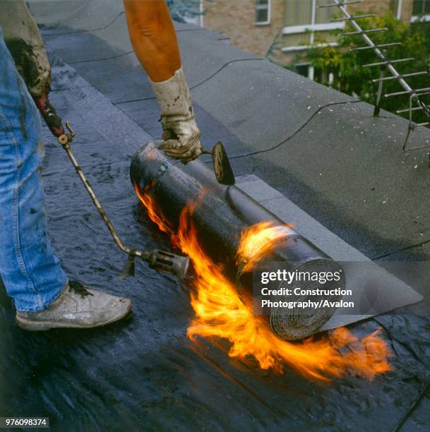 Bituminous Roofing Applying bitumen roll on a flat roof.