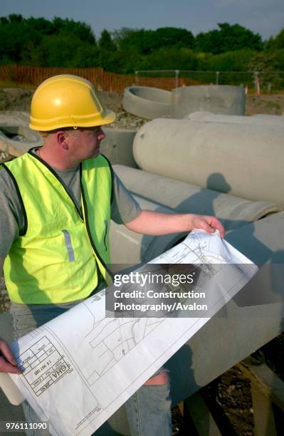 Building technician checking plan on site.