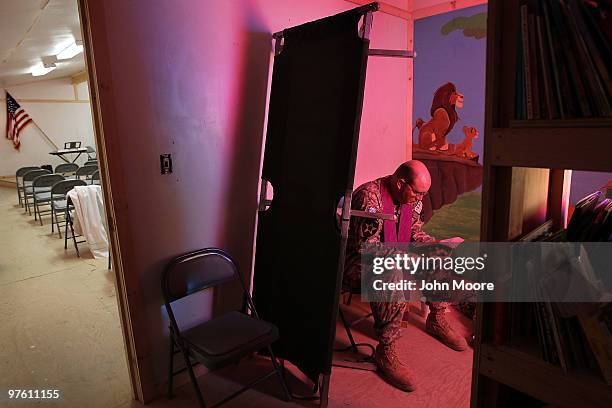 Catholic Chaplain Cpt. Carl Subler reads a prayer book behind an upturned bed cot while waiting to hear soldiers' anonymous confessions on March 10,...