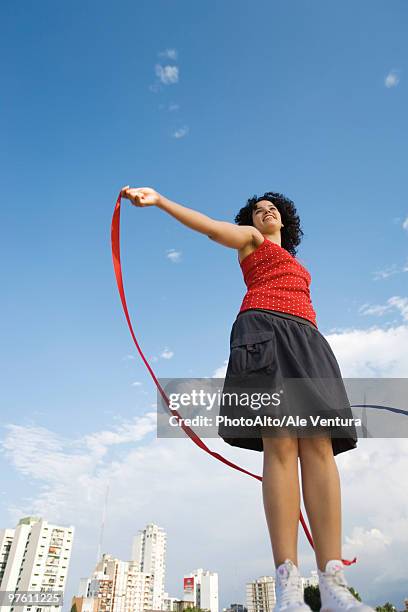 young woman holding ribbon in wind, smiling, low angle view - windy skirt - fotografias e filmes do acervo