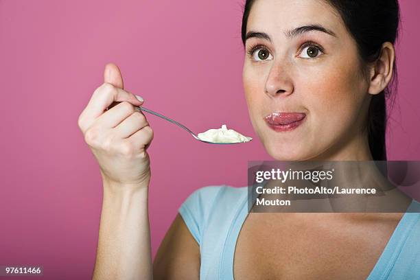 woman tasting spoon full of ice cream, licking lips - cucchiaio foto e immagini stock