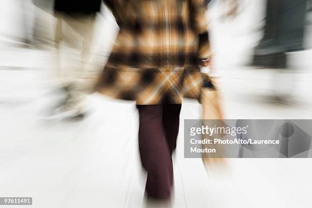 shopper walking with shopping bag in hand, rear view, cropped - mitziehen stock-fotos und bilder