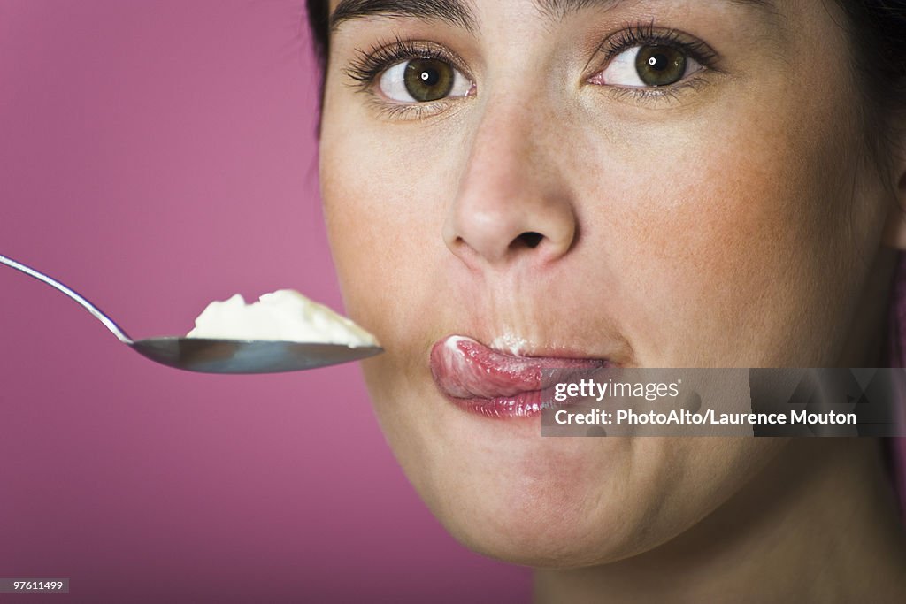 Woman with spoon full of ice cream, licking lips