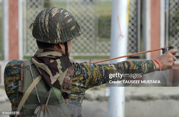 An Indian police paramilitary trooper uses a sling shot during clashes between protesters and Indian government forces in Srinagar on June 16, 2018....