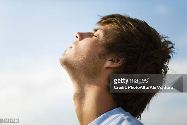 young man outdoors with head back, eyes closed - throat photos fotografías e imágenes de stock