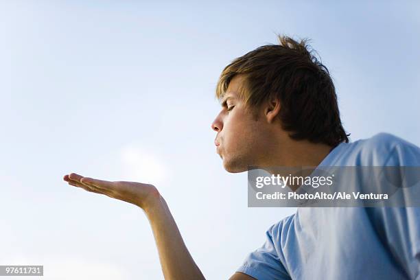 young man holding out palm, blowing, eyes closed - mandare un bacio foto e immagini stock