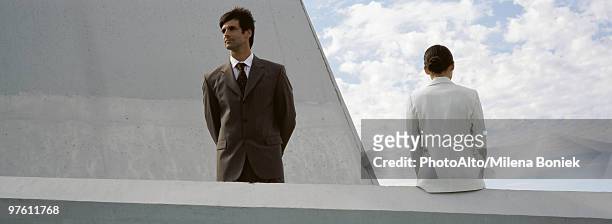 businessman admiring view from rooftop, colleague sitting on ledge nearby - buenos aires rooftop stock pictures, royalty-free photos & images