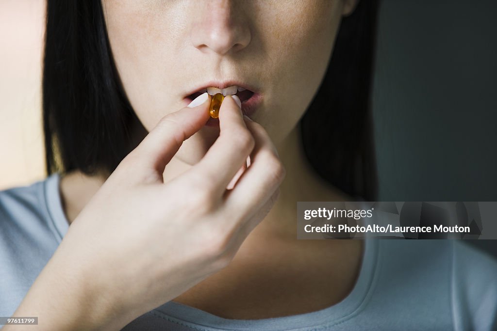 Woman taking vitamins, close-up