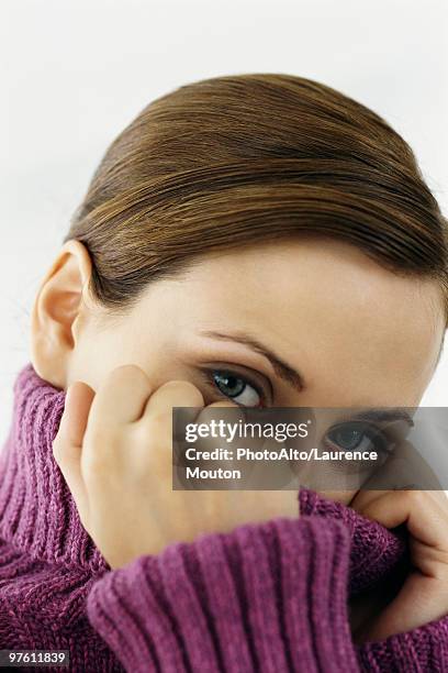 woman pulling turtleneck collar over mouth and nose, portrait - turtleneck stock pictures, royalty-free photos & images