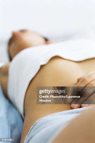 woman lying on back, hand on abdomen, close-up - femme main ventre photos et images de collection