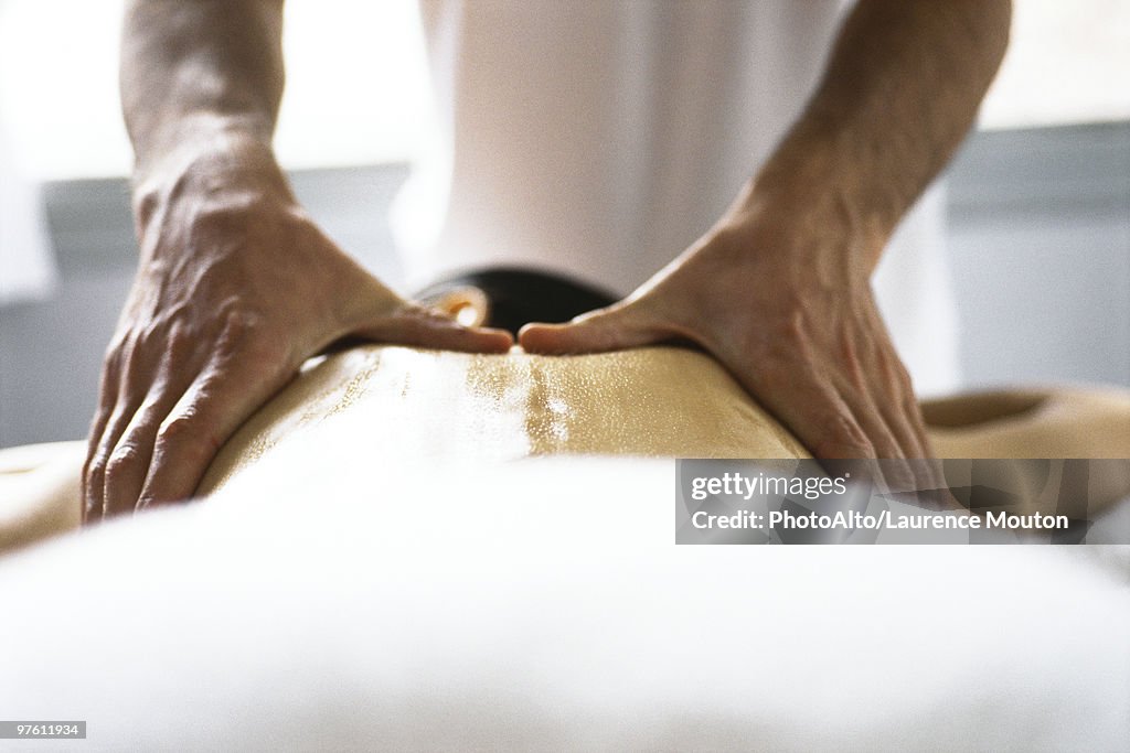 Hands of massage therapist massaging woman's back