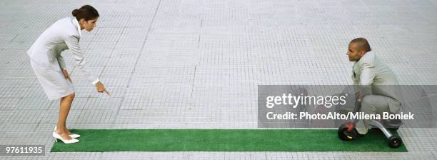 businesswoman leaning forward pointing sternly at ground, man pedaling tricycle towards her - hierarquia de corporação imagens e fotografias de stock