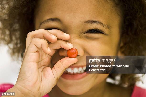 little girl holding up piece of candy - 人間の鼻 ストックフォトと画像