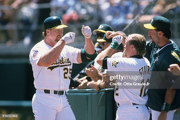 Mark McGwire of the Oakland Athletics fist bumps teammate Matt Stairs after hitting a home run during the game against the Seattle Mariners at...