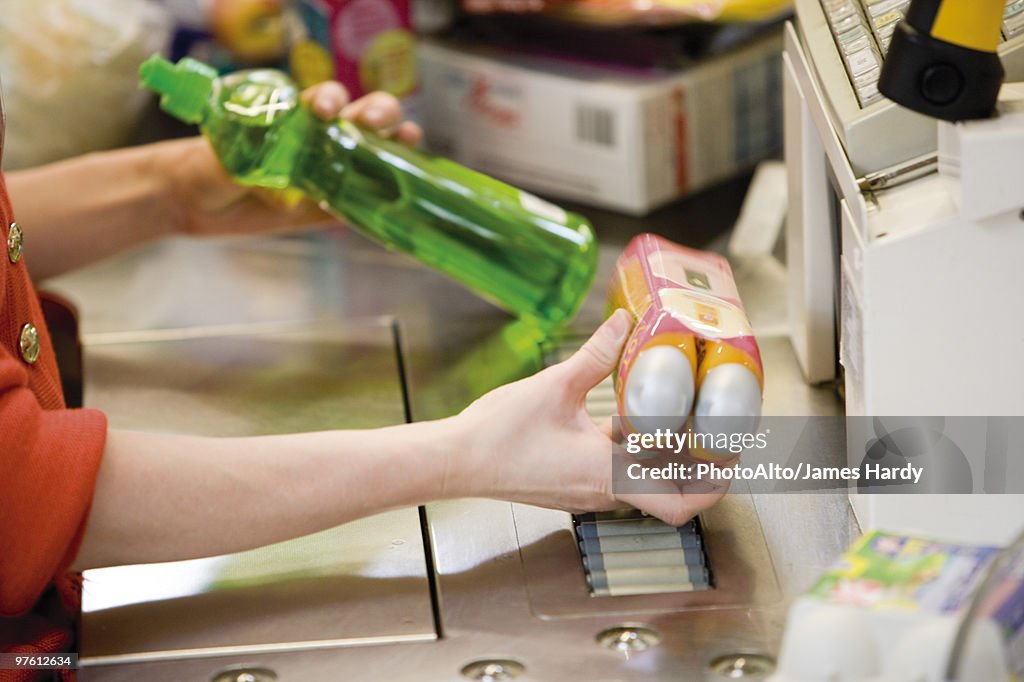 Cashier scanning items at checkout counter, cropped