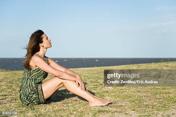 woman sitting on grass barefoot, relaxing - hugging knees bildbanksfoton och bilder