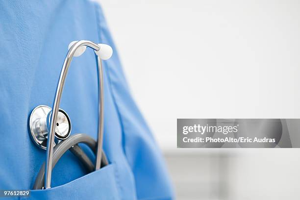 stethoscope in pocket of scrub top - stethoskop stock-fotos und bilder