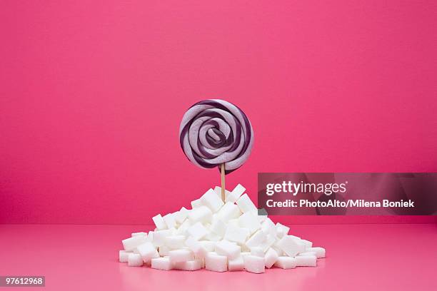 food concept, lollipop sticking out from pile of sugar cubes - sugar cube stock pictures, royalty-free photos & images