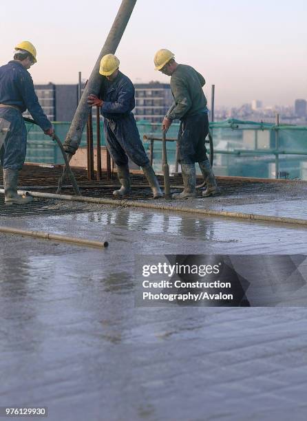 Pouring and compacting in situ reinforced concrete using pump and vibrating poker during reinforced floor slab construction at the Diwa building...