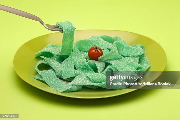 food concept, plate of green gummy candy arranged like pasta, topped with cherry tomato - tart stock-fotos und bilder