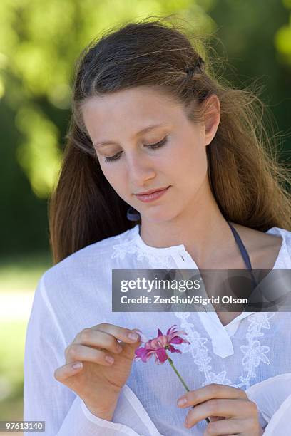 young woman plucking petals from flower - 花びら占い ストックフォトと画像
