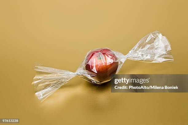 food concept, fresh apple inside cellophane candy wrapper - candy wrapper stockfoto's en -beelden