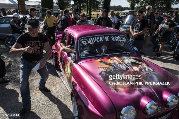 Fans stand next to a car painted with Johnny Hallyday portraits during the inauguration of a statue of the late French rocker installed in the...