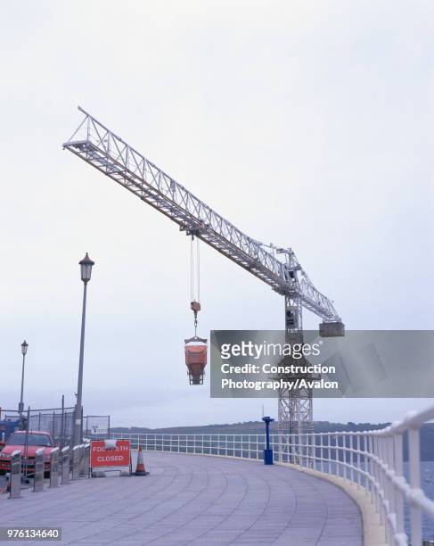 Tower crane lifting concrete hopper over closed footway Renovation of Tinside swimming pool Plymouth Hoe, Plymouth, United Kingdom.