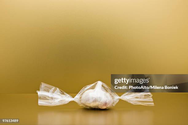 food concept, head of garlic inside of cellophane candy wrapper - cellophane stock pictures, royalty-free photos & images