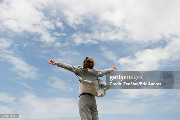 businessman with arms outstretched against cloudy sky, rear view - man outstretched arms foto e immagini stock