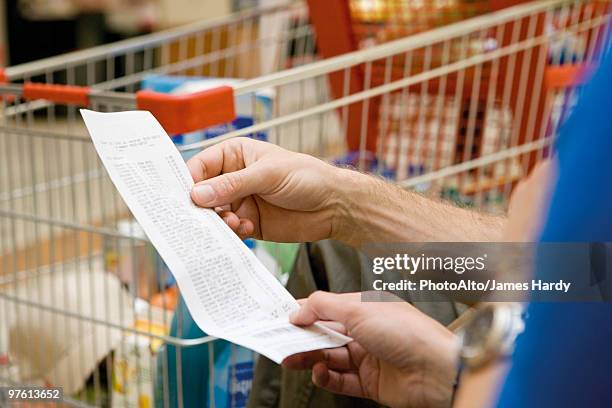 shopper reviewing receipt, cropped - carrito de la compra fotografías e imágenes de stock