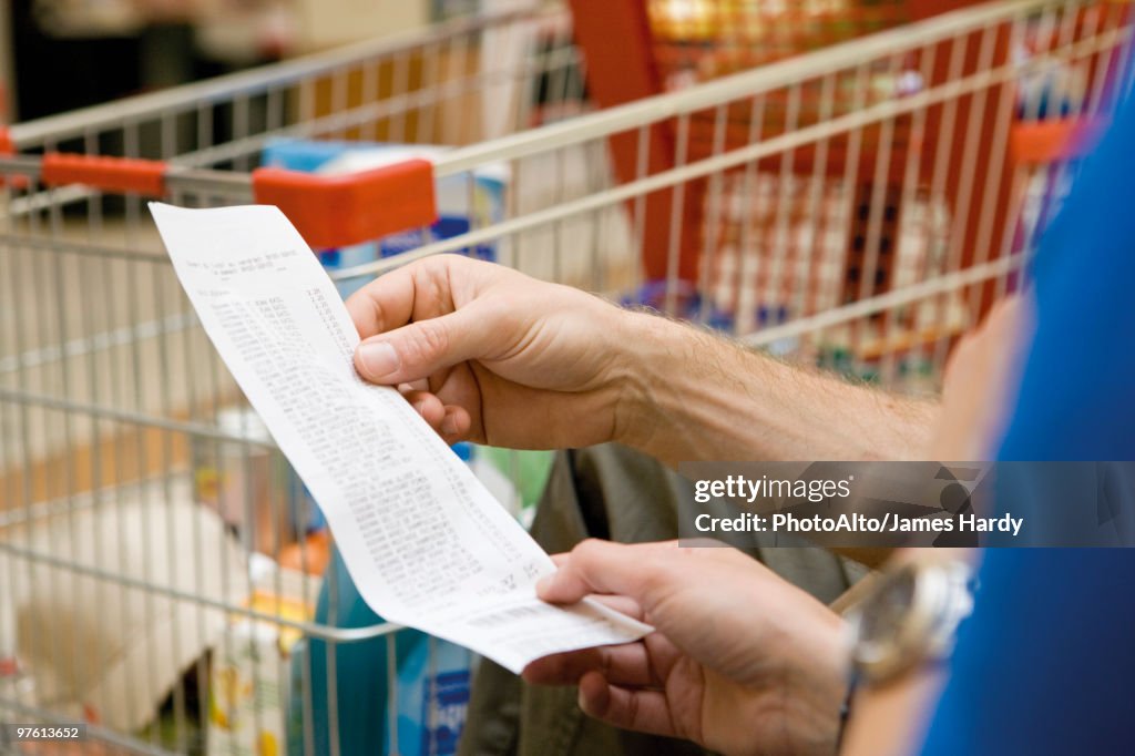 Shopper reviewing receipt, cropped