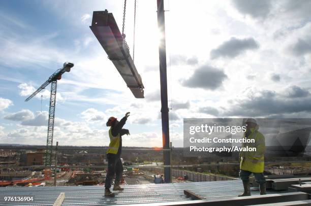 Construction workers receiving steel beams by crane at construction of new supermarket, Milton Keynes, Buckinghamshire, UK .