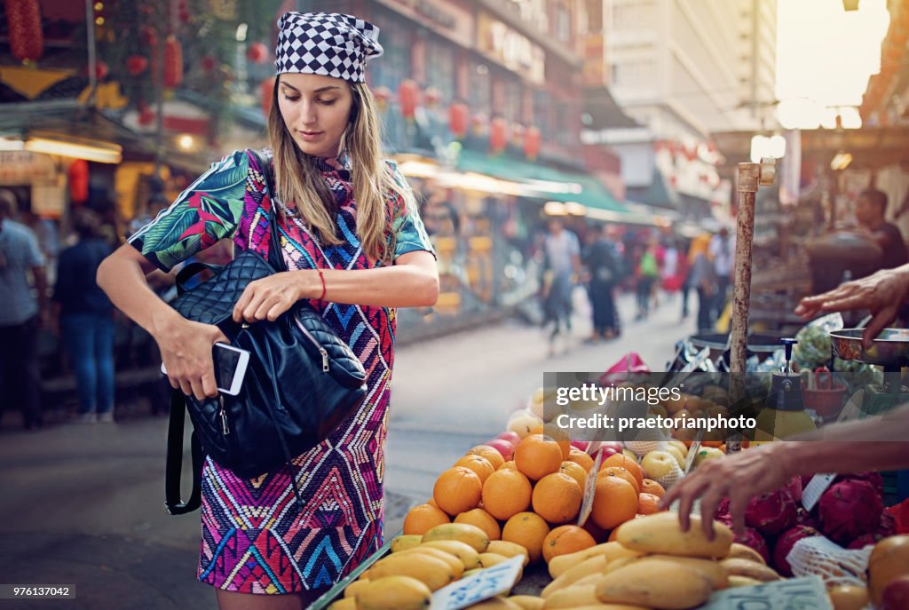Young girl is buying fruits and vegetables at the marketplace in the Chinatown