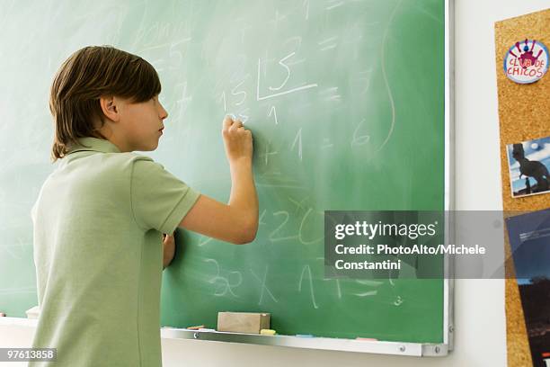 boy writing with chalk on blackboard - mathematics imagens e fotografias de stock