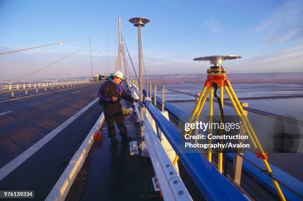 Surveyor taking readings on Pont de Normandie bridge France.