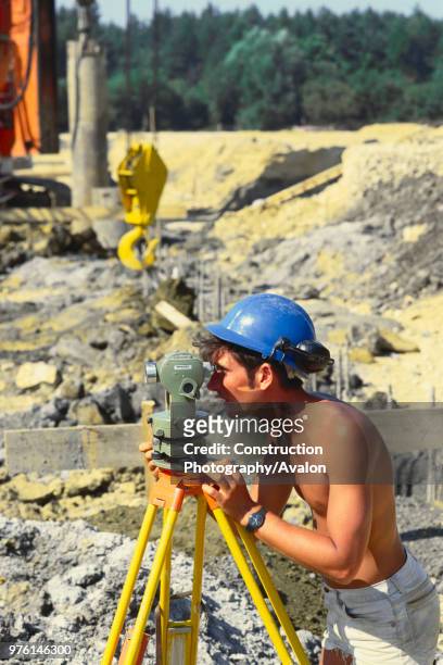 Surveyor taking measurements on site bare-chested.