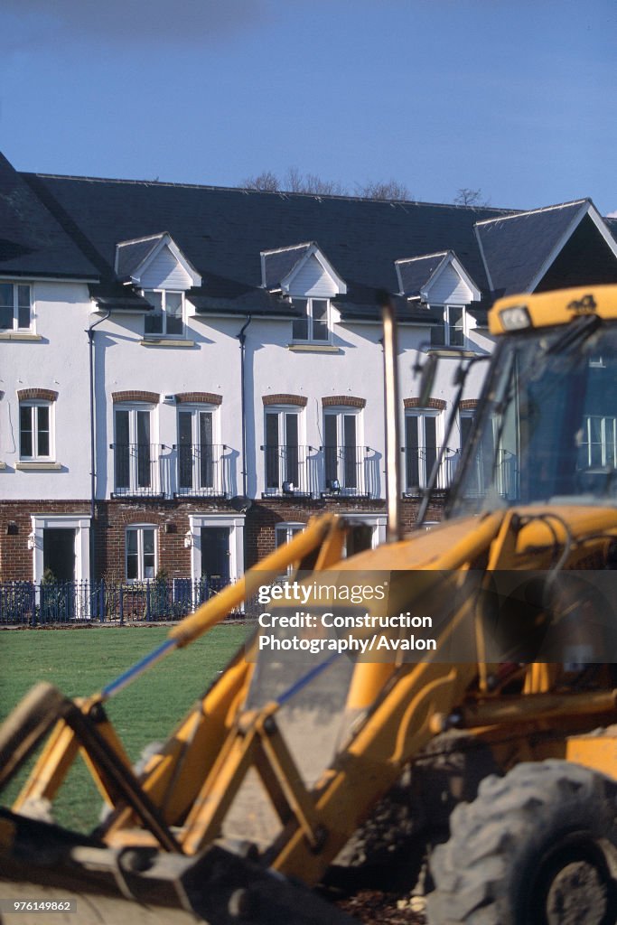JCB backhoe loader in front of new residential development.