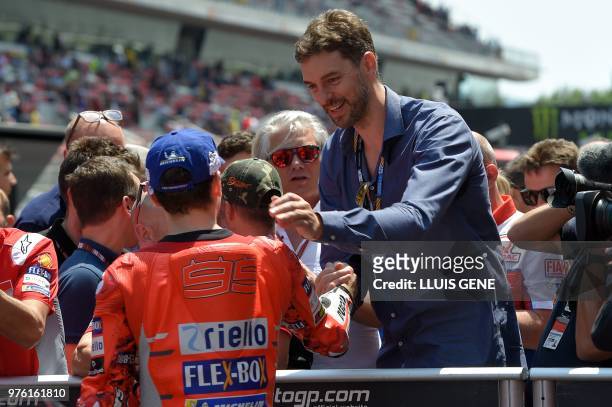 Ducati Team's Spanish rider Jorge Lorenzo is congratulated by Spanish basketball player Pau Gasol after taking the pole position during the Catalunya...