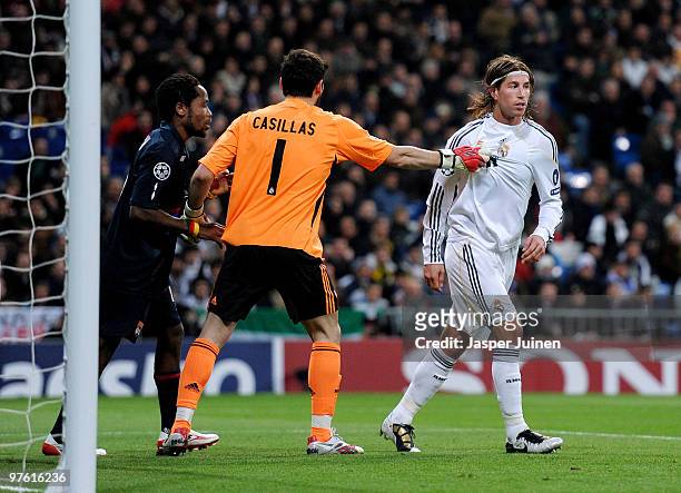 Goalkeeper Iker Casillas of Real Madrid separates his team mate Sergio Ramos and Jean II Makoun of Lyon during the UEFA Champions League round of 16...