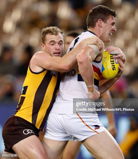 Josh Jenkins of the Crows is tackled by Tom Mitchell of the Hawks during the 2018 AFL round 13 match between the Hawthorn Hawks and the Adelaide...