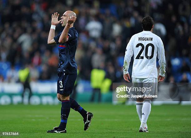 Cris captain of Lyon celebrates as Gonzalo Higuain of Real Madrid trudges off the pitch during the UEFA Champions League round of 16 second leg match...