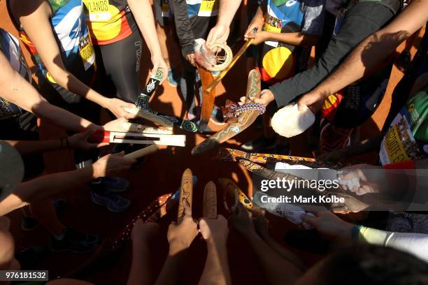Runners hold their special made relay batons together before competing during the Uluru Relay Run as part of the National Deadly Fun Run...
