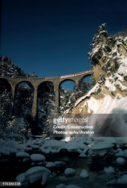 Local train of Rhaetian railway crossing Landwasser viaduct, Swiss Alps, Canton of Grisons, Switzerland.