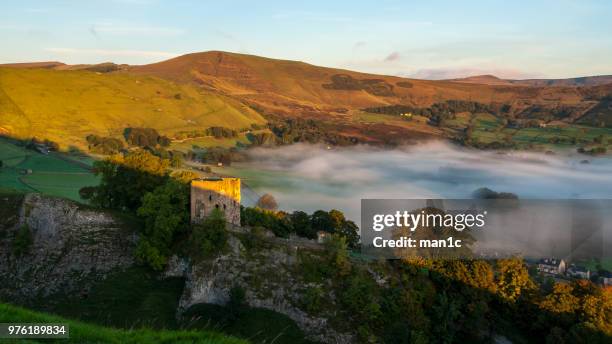 view of ruins of peveril castle in peak district and fog in valley, castleton, derbyshire, england, uk - peveril castle - fotografias e filmes do acervo