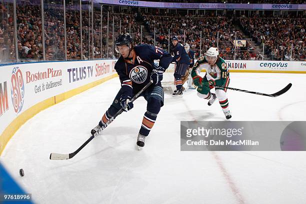 Tom Gilbert of the Edmonton Oilers skates for the puck against Andrew Brunette of the Minnesota Wild on March 5, 2010 at Rexall Place in Edmonton,...